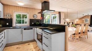 Una cocina moderna con armarios blancos, encimera negra y techo de madera.