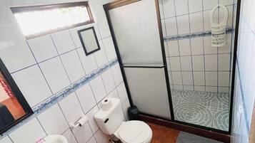 Un baño con inodoro, lavabo y zona de ducha.