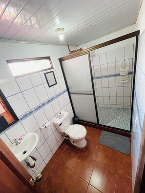 Une salle de bain comprenant des toilettes, un lavabo et un espace douche.