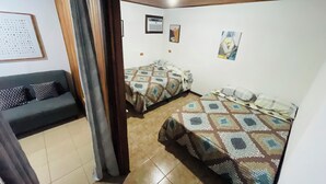 A room with two beds, a sofa, and a ceiling fan.