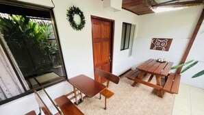 A dining area with a wooden table and benches, a door, a window, and a wall-mounted decoration.