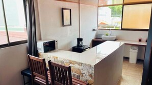 A small kitchen with a stone countertop, a coffee maker, and a sink.
