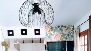 Une cuisine moderne avec des armoires blanches, un ventilateur de plafond noir et un téléviseur à écran plat fixé au mur.