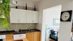 Une cuisine moderne avec des meubles blancs, un plan de travail noir et un coin repas comprenant une table et des chaises.