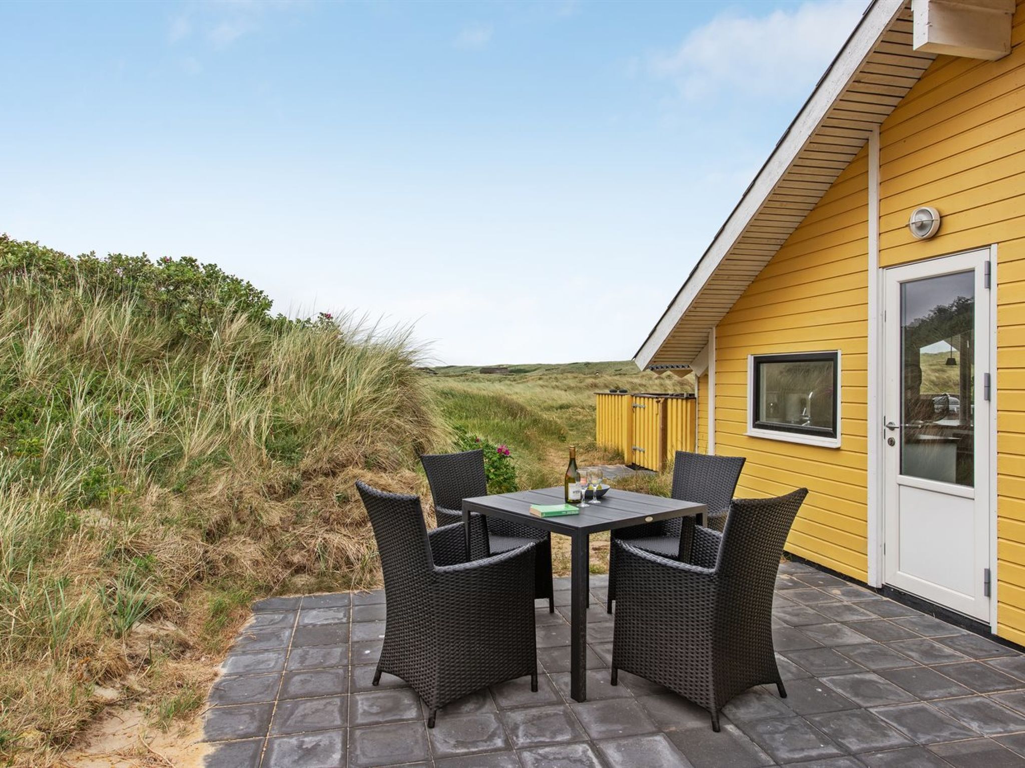 Un bâtiment jaune doté d’un patio comprenant une table et quatre chaises.