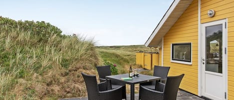 Un bâtiment jaune doté d’un patio comprenant une table et quatre chaises.