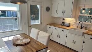 Une cuisine moderne avec des meubles blancs, un plan de travail en bois et un évier.
