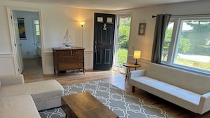Un salon comprenant un canapé, une table basse en bois, un tapis à motifs, une lampe et une petite table avec une lampe.