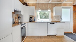 Een moderne keuken met witte kasten, houten vloeren en een groot raam dat voor natuurlijk licht zorgt.