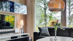 Een moderne woonkamer met een zwarte leren bank, een ronde salontafel en een aan de muur bevestigde televisie.