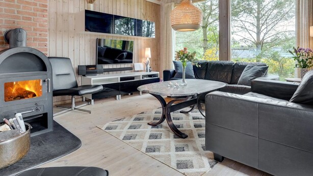 Een moderne woonkamer met een open haard, een aan de muur bevestigde televisie, een bank en een salontafel.
