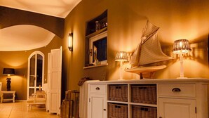 A hallway with a white console table, wicker baskets, and a sailboat model. - Fantastically beautiful ambience on 93sqm in Peschiera, 5 min=lake 7min=center, balcony (Peschiera del Garda)
