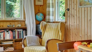 Ein gemütliches Zimmer mit einer Holzbücherreolen, einem gestreiften Sessel und einem Globus auf einem Regal.