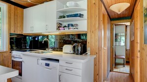 Eine moderne Küche mit Holzschränken, einem Backofen, einer Spülmaschine und einem Spülbecken.