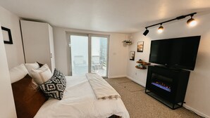 Et soveværelse med seng, fjernsyn, pejs og balkon med udsigt.