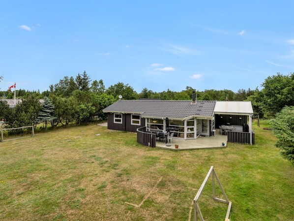 Een tweelaags huis met een overdekt terras en een omheinde tuin.