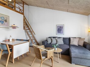Un espacio habitable moderno con comedor, escalera, sofá y una obra de arte colgada en la pared.