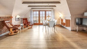 A spacious loft with exposed wooden beams, a fireplace, leather chairs, a dining area, and a TV. - "Vangja" - 700m to the fjord by Interhome (Hvide Sande)