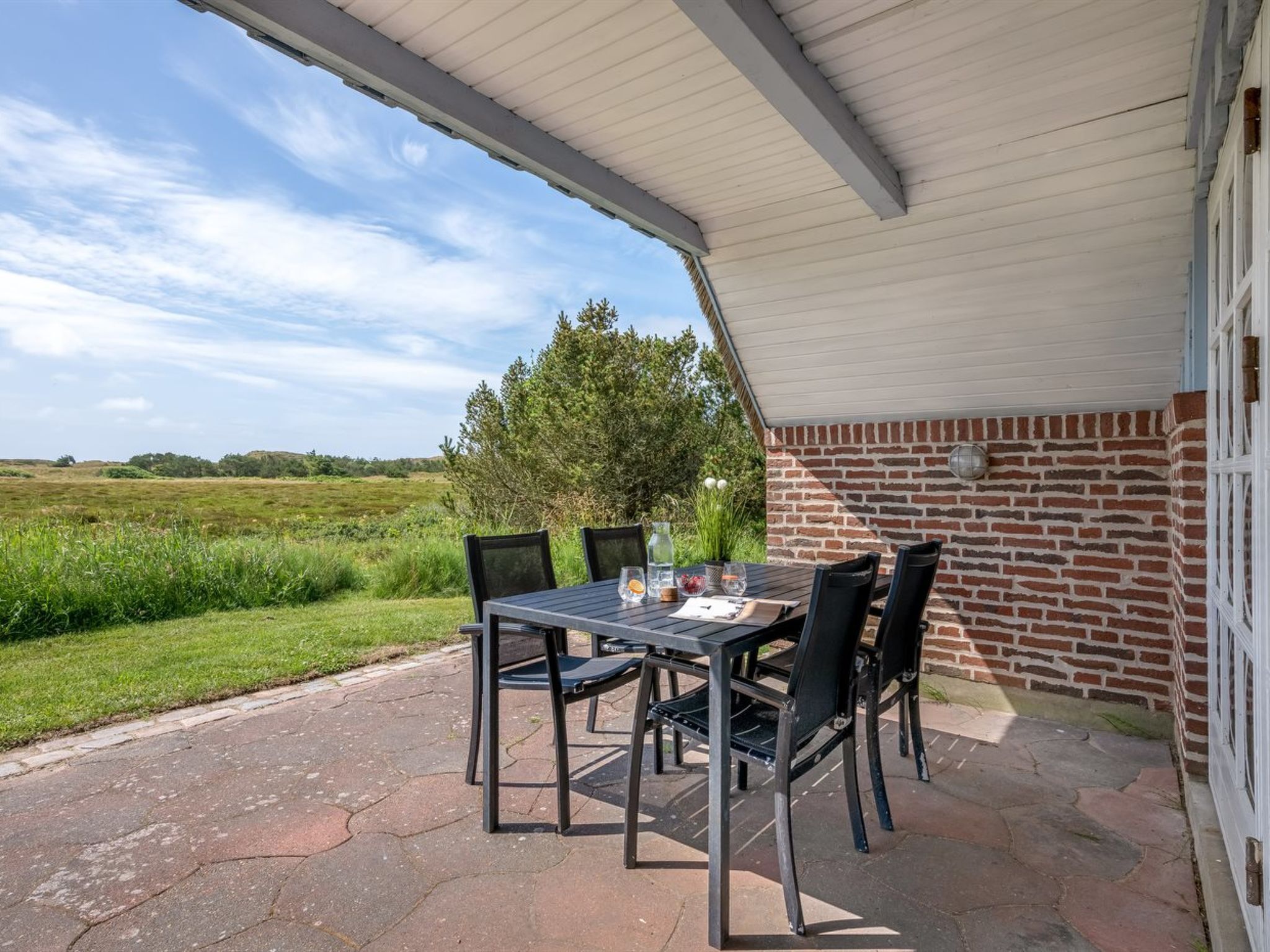 En udendørs terrasse med murstensvæg og et overdækket område.