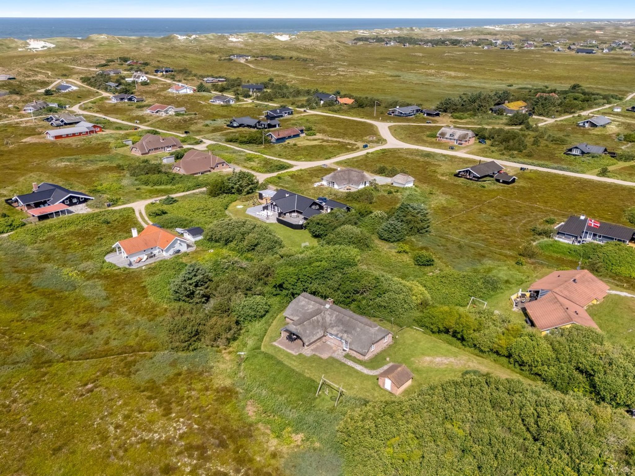 An aerial view of a residential area with houses, roads, and greenery.