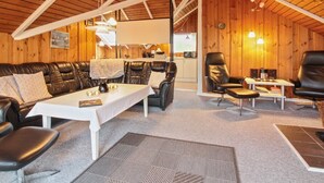 A cozy cabin interior with a leather sofa, a dining table, and a fireplace.