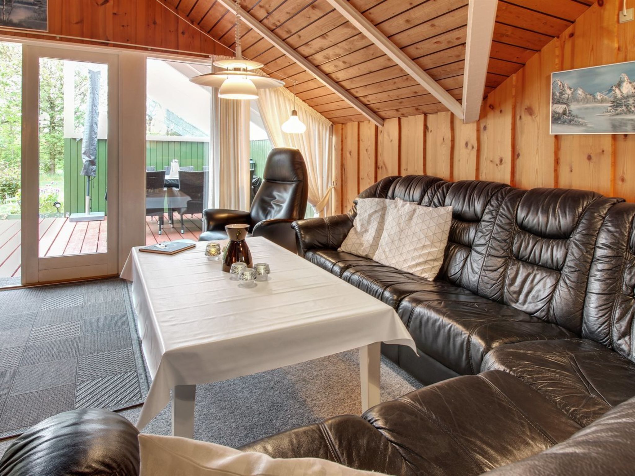 Een gezellige kamer met een leren bank, een tafel met decoratieve spullen en uitzicht op een terras.