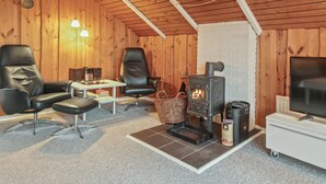 A cozy room with a fireplace, leather chairs, a television, and a small table.