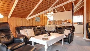 A cozy room with a leather sofa, a dining table, and a kitchen in the background.