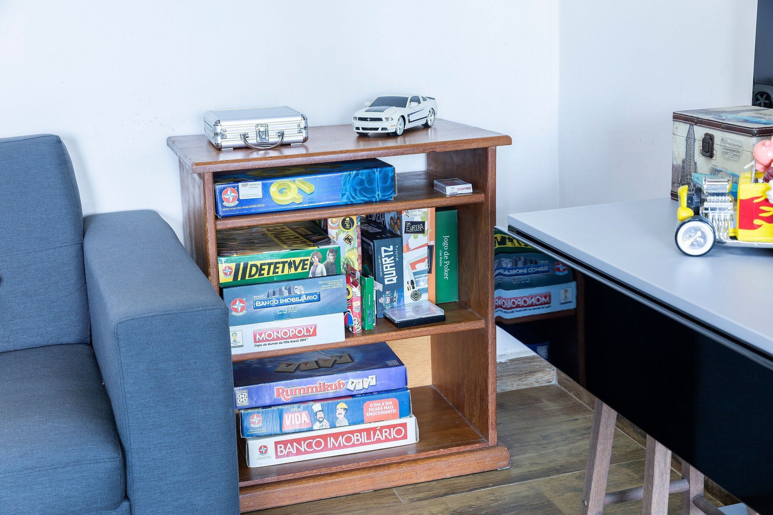 Ein Bücherregal aus Holz mit Gesellschaftsspielen und einem Spielzeugauto.