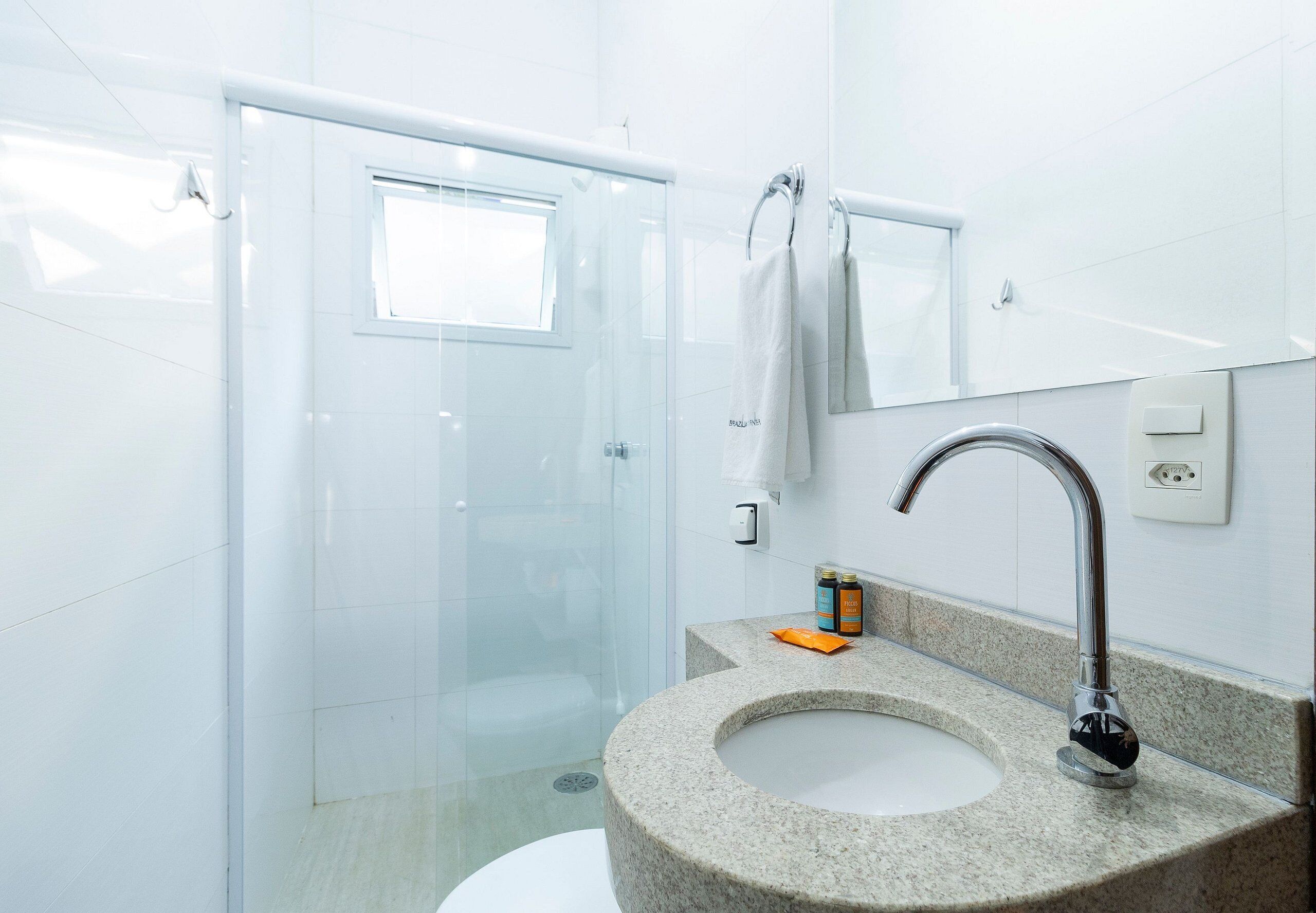 A modern bathroom with a granite sink, a glass shower enclosure, and a mirror above the sink.