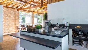 Une cuisine moderne dotée d’un grand îlot central, de poutres en bois au plafond et d’un mur en briques.