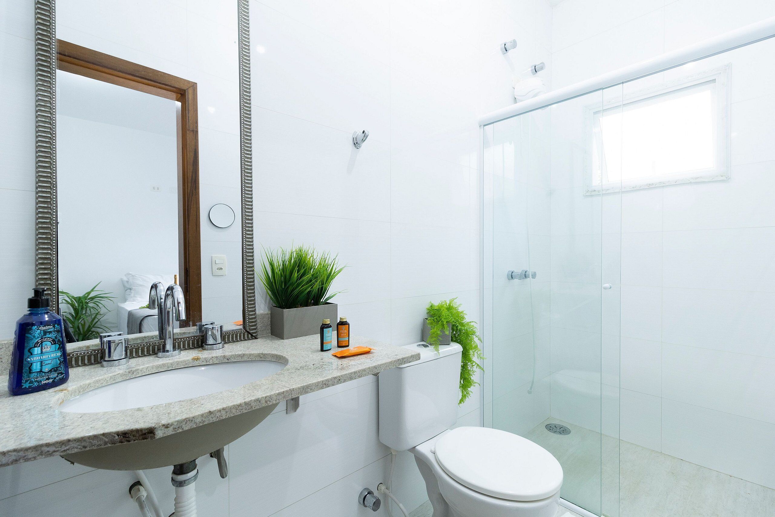 Une salle de bain moderne avec un grand miroir, un lavabo, des toilettes et une douche à parois de verre.