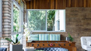 Une pièce chaleureuse avec un mur en briques, un plafond en bois, une grande fenêtre, un canapé, une table et une chaise.