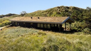 A modern building with a flat roof, a covered outdoor area, and a natural, hilly backdrop. - "Marite" - 200m from the sea by Interhome (Pandrup)
