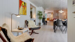 A modern interior with a dining area, two leather chairs with fur throws, a white table, and a large painting on the wall. - "Orvokki" - 125m from the sea by Interhome (Sæby)