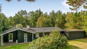A single-story building with a dark exterior, a covered porch, and a small attached shed. - "Orvokki" - 125m from the sea by Interhome (Sæby)