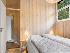 Une chambre avec un mur en bois, une fenêtre, un lit et une table de chevet.