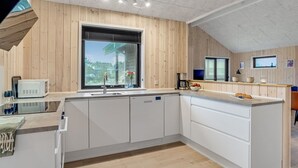 Una cocina moderna con paneles de madera, un ventanal grande y una isla integrada.