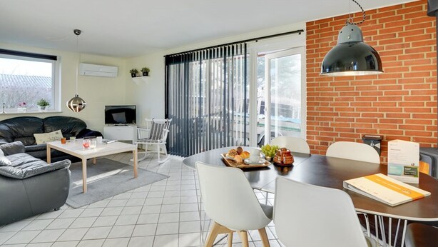 Een moderne woonkamer met een bank, televisie, eettafel en stoelen.