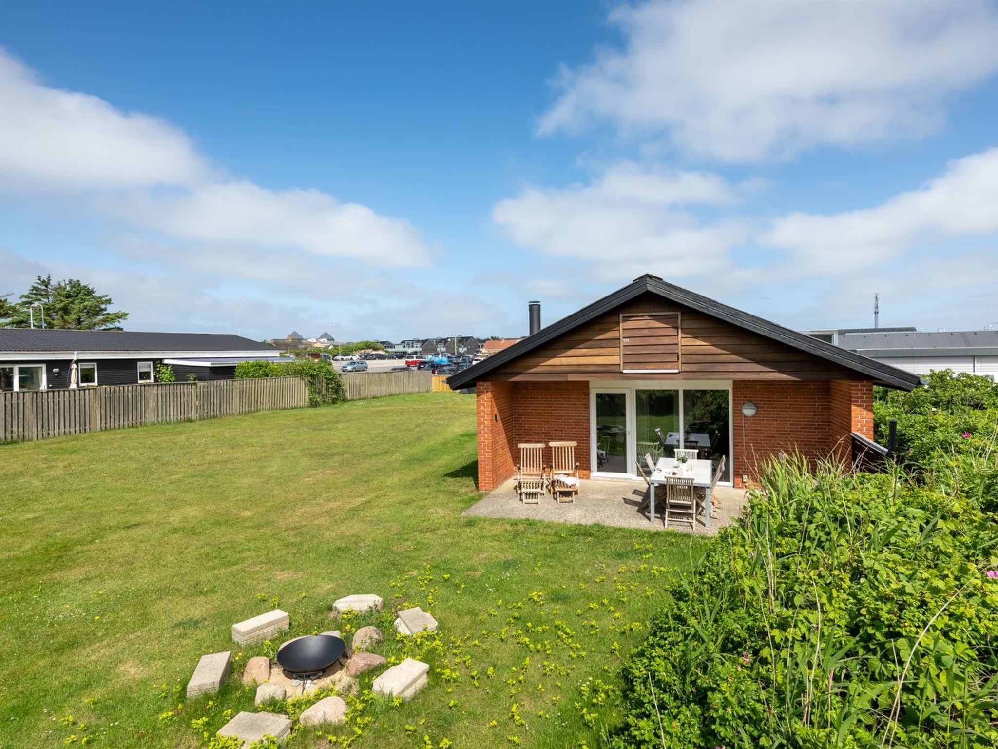 Une petite maison en briques avec un patio, un foyer extérieur et une cour clôturée.