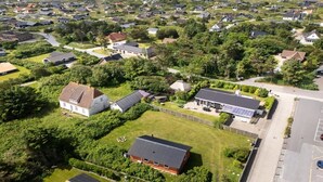Luchtbeeld van een woonwijk met huizen, groene zones en een parkeerplaats.