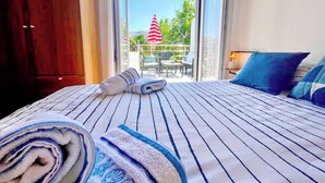 A hotel room with a bed, a view of the outdoor area, and a balcony with a table and chairs. - Holiday apartment with balcony (Baška)