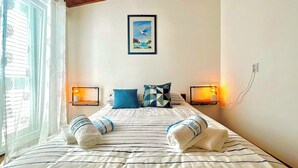 A neatly made bed with striped bedding, two pillows, and two towels. There is a framed picture on the wall above the bed. - Holiday apartment with balcony (Baška)