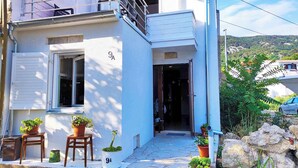 A two-story building with a balcony, a door marked with the number 9A, and potted plants on the ground floor. - Holiday apartment with balcony (Baška)