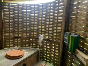 A wooden room with a bench and a small table, a wooden lattice partition, and a power strip on the wall. - Beautiful Riverside Lodge in Newbridge on Wye (Builth Wells)