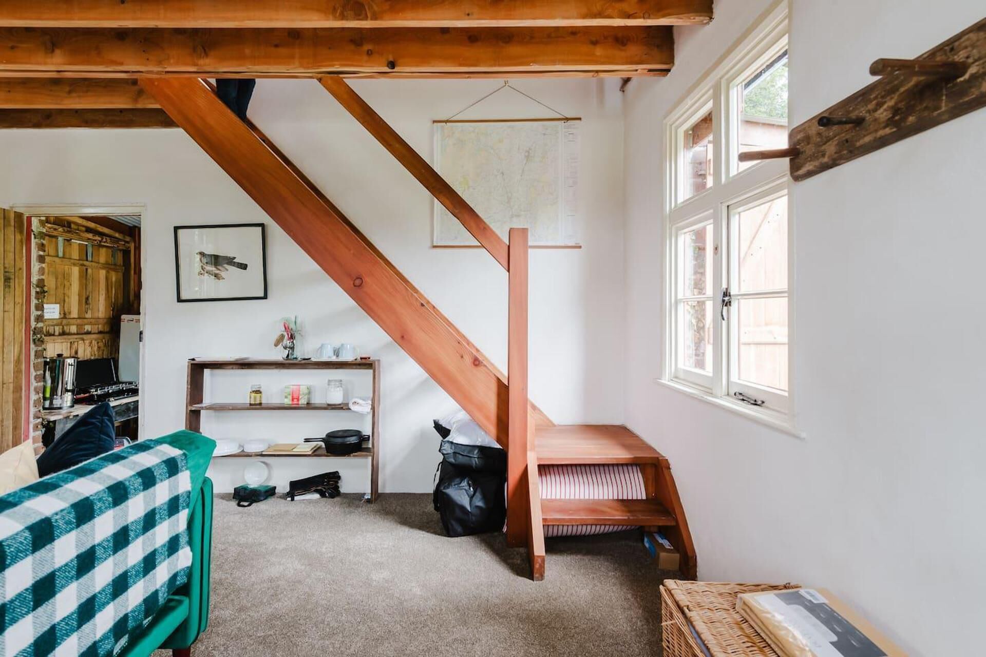 Una habitación con escalera de madera, zona de cocina y ventana con vistas.