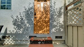Una casa con puerta de madera, un pequeño porche con escalones y una puerta de garaje.