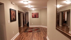 Un couloir doté d’un plancher en bois, de tableaux encadrés accrochés aux murs et d’un tapis à motifs.