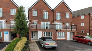A two-story brick apartment building with a car parked in the driveway. - 5 Bed House - Sleeps 9 - Pets - Garden - Parking (Ashford)