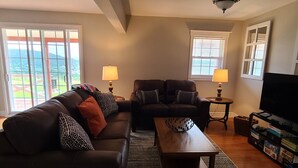 A living room with two sofas, a coffee table, and a TV. There are two lamps on side tables. - Spaniard's Perch - Incredible Ocean View (Spaniard's Bay)